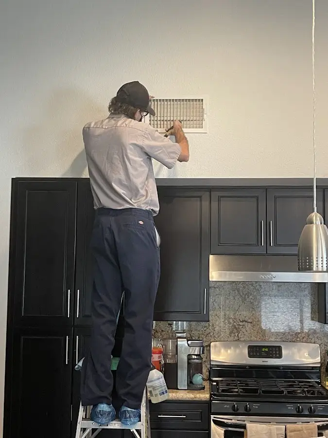 Technician inspecting an air vent during HVAC service in East Fishkill